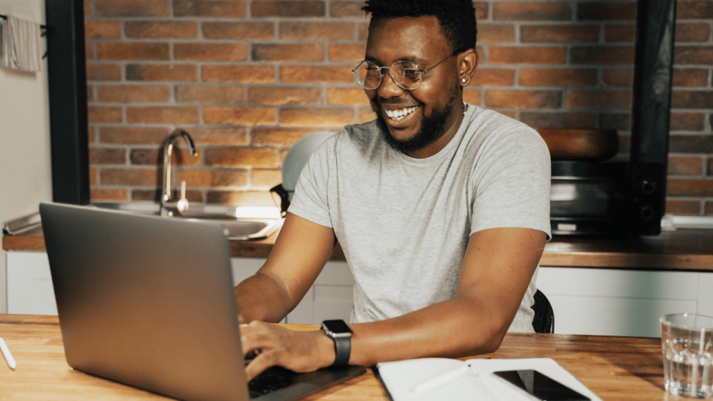 A man smiles while working on his laptop