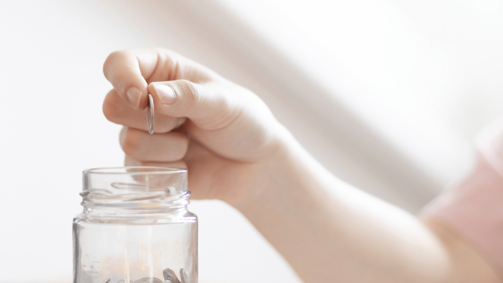 A person putting coins in a jar