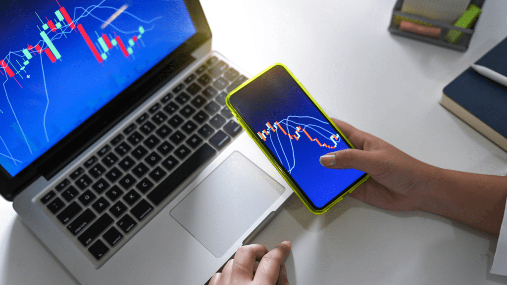 A person using smartphone and laptop to monitor stock market