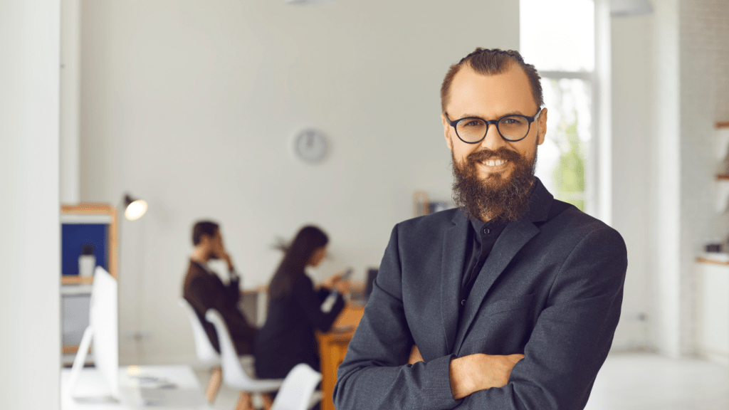 A businessman standing with arms crossed against a blurred office background