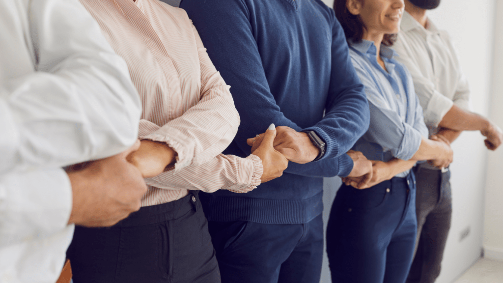 Colleagues standing in rows holding hands