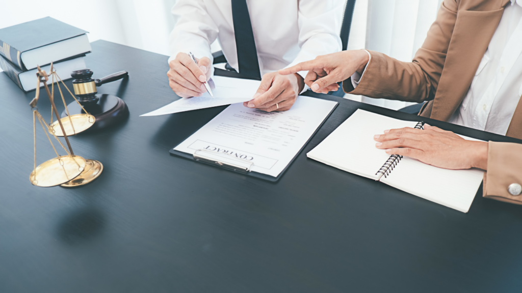 two people sitting at a desk signing papers