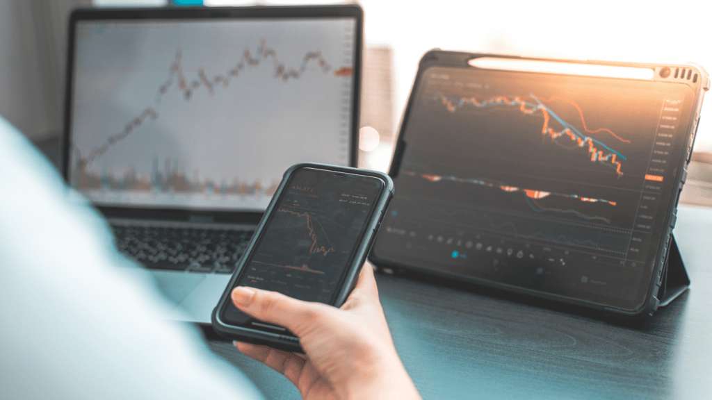 A person using smartphone and laptop to monitor stock market