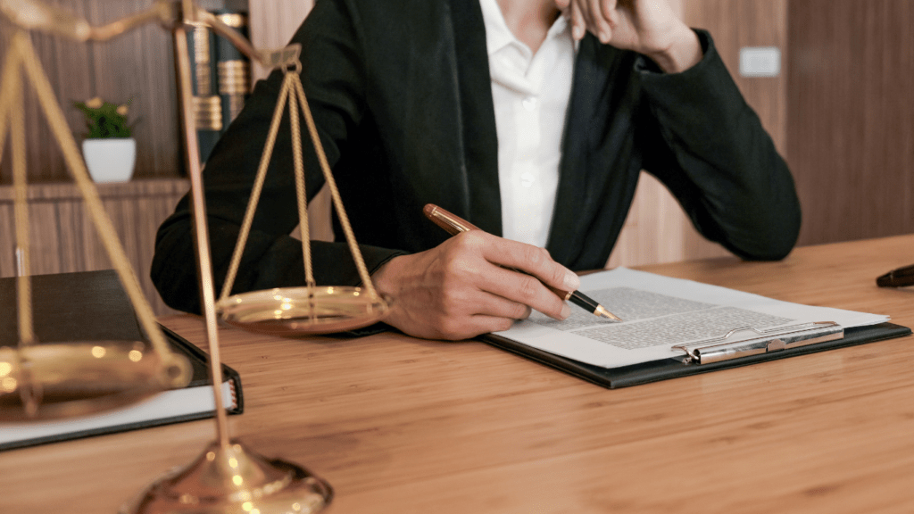 a person in a suit sitting at a desk with a scale of justice