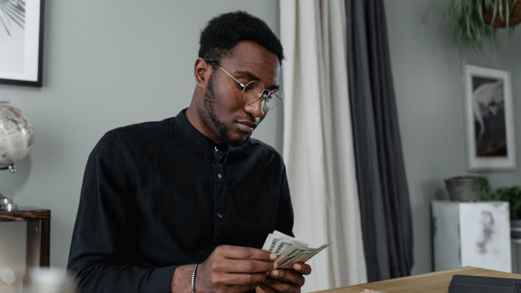 a person holding a stack of cash in front of a desk