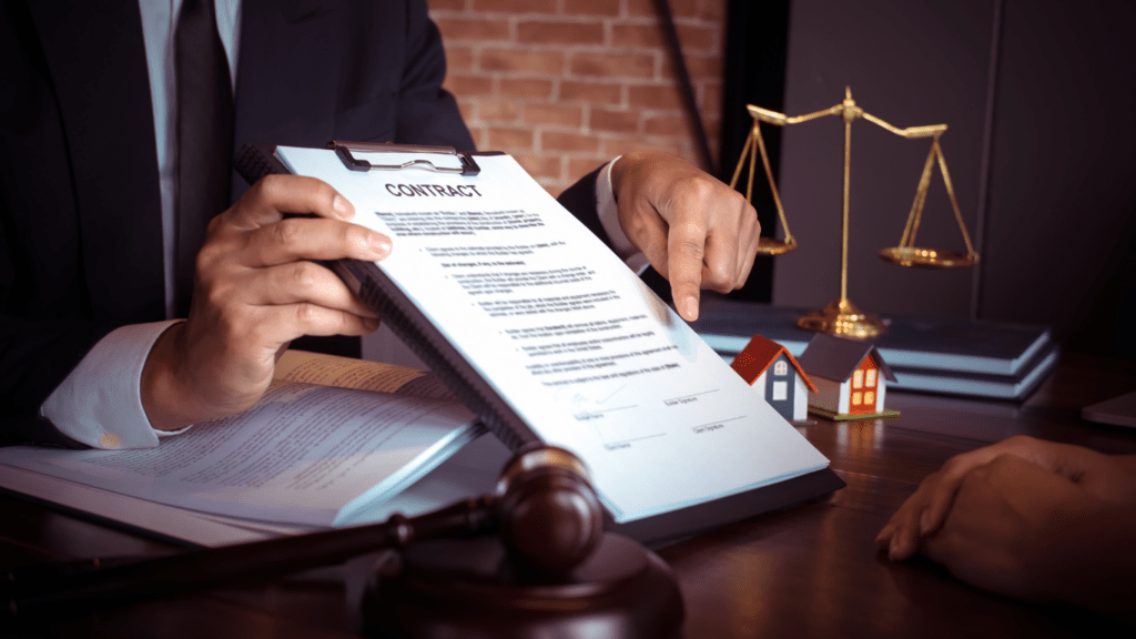 A person signing a contract in front of a table with a scale of justice