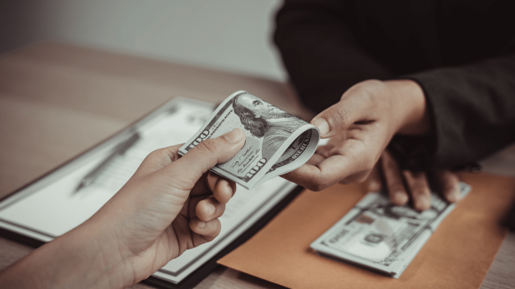 a person handing money to another person at a desk