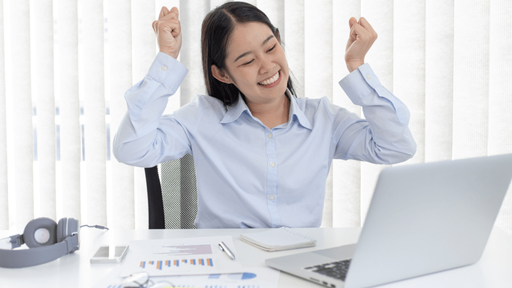 a person is sitting at their desk with their arms up in the air