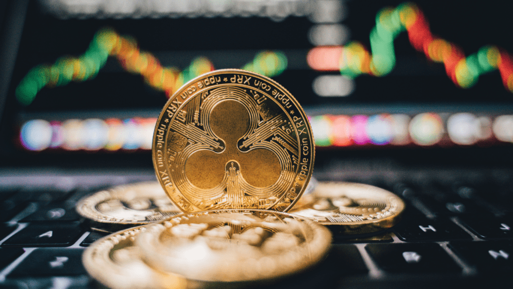 bitcoin and gold coins on a table with a stock market screen in the background